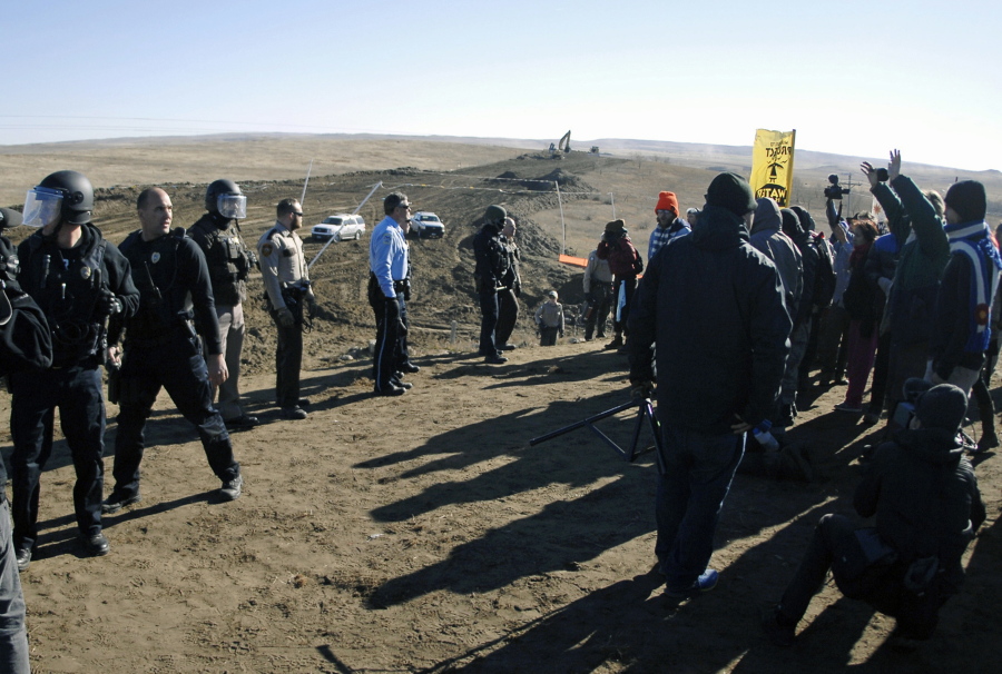 FILE - In this Nov. 11, 2016, file photo, law enforcement try to move Dakota Access pipeline protesters further down during a protest at a pipeline construction site south of St. Anthony, N.D. The Trump administration has denied a request from Republican North Dakota Gov. Doug Burgum for a “major disaster declaration” to help cover some of the estimated $38 million cost to police protests of the pipeline.