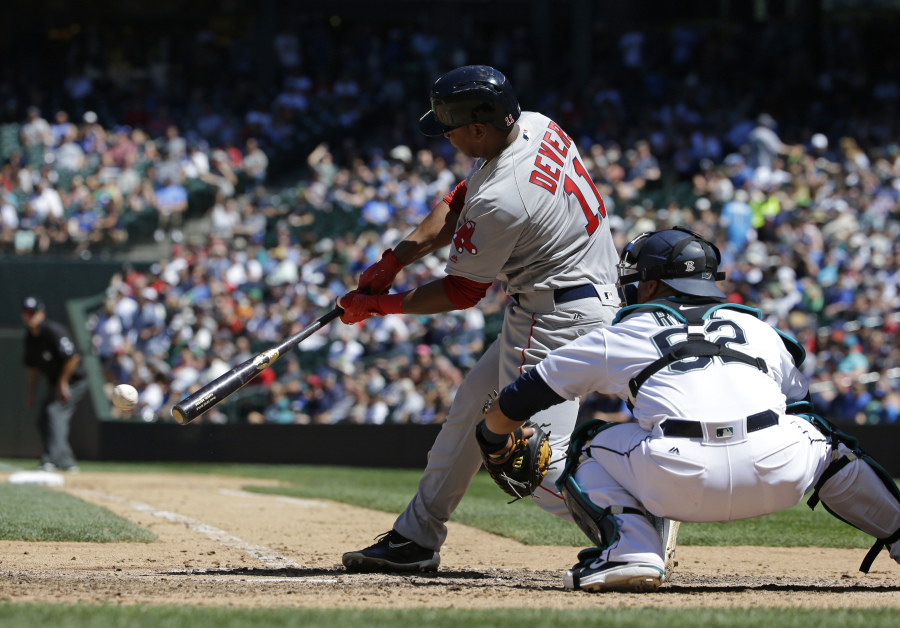 Boston Red Sox’s Rafael Devers hits a single in the seventh inning of a baseball game as Seattle Mariners catcher Carlos Ruiz looks on, Wednesday, July 26, 2017, in Seattle. (AP Photo/Ted S.