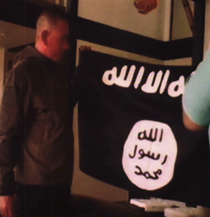 FILE - In this July 8, 2017 file image taken from FBI video and provided by the U.S. Attorney’s Office in Hawaii on July 13, 2017, Army Sgt. 1st Class Ikaika Kang holds an Islamic State group flag after allegedly pledging allegiance to the terror group at a house in Honolulu. A federal grand jury in Hawaii has indicted Kang for attempting to provide material support to the Islamic State group. Kang was indicted Friday, July 21 after he was arrested by an FBI SWAT team on July 8. Kang was ordered held without bail. Because of the indictment, Kang will no longer have a preliminary hearing that was scheduled for Monday, July 24.