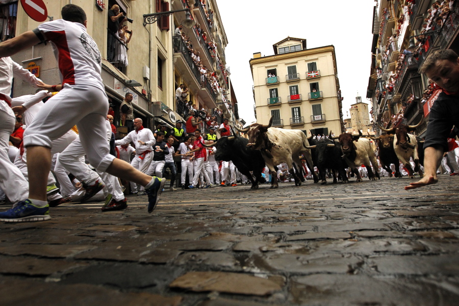 Revelers run in front of Fuente Ymbro’s fighting bulls during the running of the bulls Monday at the San Fermin Festival in Pamplona, Spain.