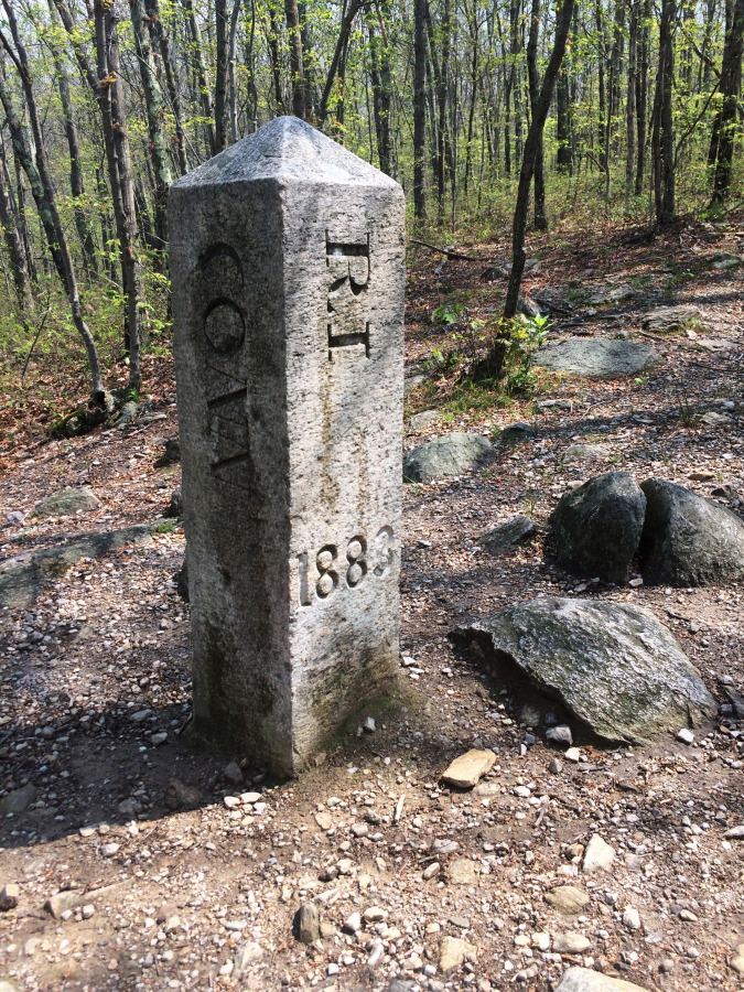 The granite monument that marks the spot where Connecticut, Massachusetts and Rhode Island meet in Thompson, Conn. There’s an unusual travel hobby that has people visiting the woods of Thompson, and other remote spots across the country. The visitors are looking for tripoints, spots where three states meet.