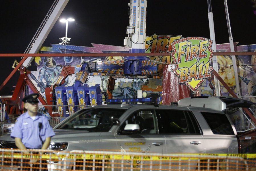 Authorities stand near the Fire Ball amusement ride after the ride malfunctioned injuring several at the Ohio State Fair, Wednesday in Columbus, Ohio. Some of the victims were thrown from the ride when it malfunctioned Wednesday night, said Columbus Fire Battalion Chief Steve Martin. (Barbara J.