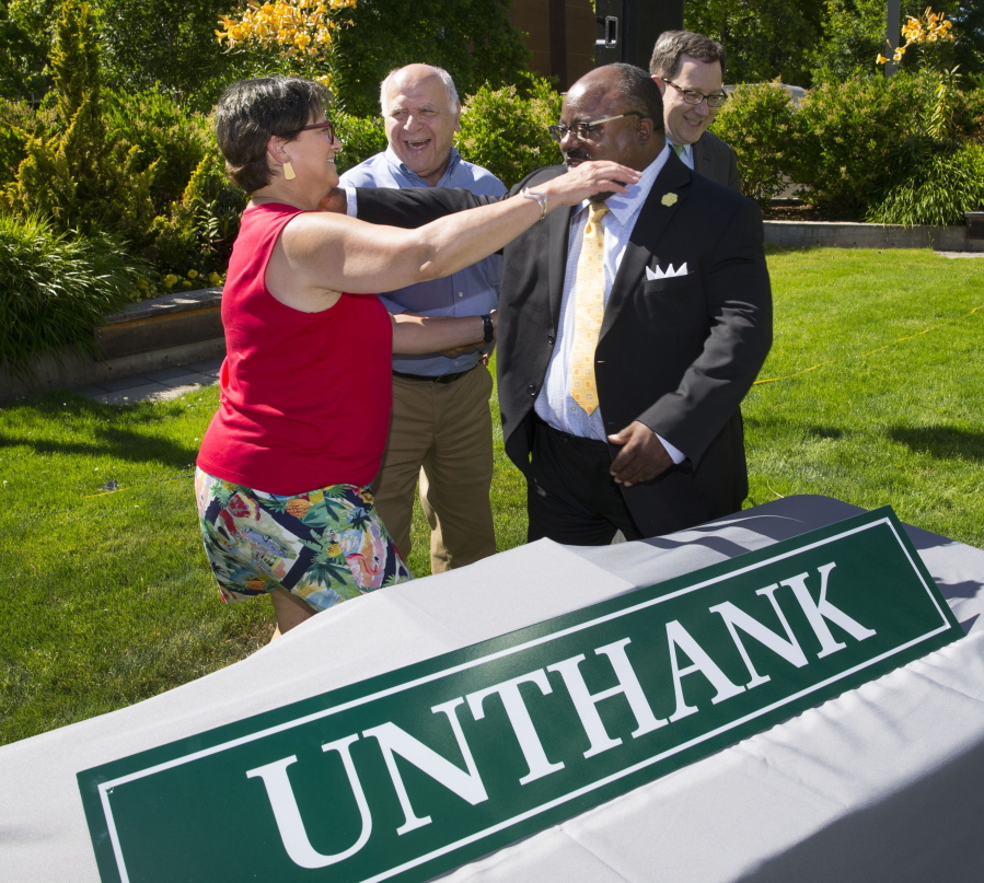 In this Tuesday, July 11, 2017 photo, DeNorval Unthank Jr.’s daughter Libby Tower, left,, local architect Otto Poticha, Eugene Councilman Greg Evans and University of Oregon President Michael Schill celebrate the unveiling of a sign that will adorn the renamed residence hall at the University of Oregon in Eugene, Ore., during a ceremony the Ford Alumni Center. Unthank was the first black man to graduate from the UO’s architecture school, and he went on to design buildings throughout the Northwest. The dormitory was renamed because of the Ku Klux Klan past of its former namesake.