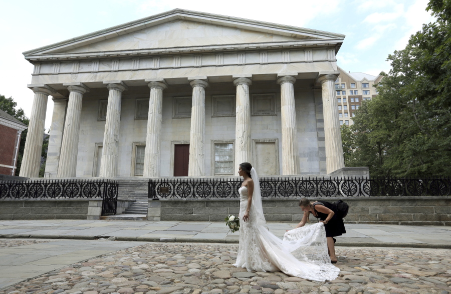 A photographer adjusts Yifat Ayalon’s wedding dress as she has photos taken in front of the Second Bank of the United States July 15, in Philadelphia.