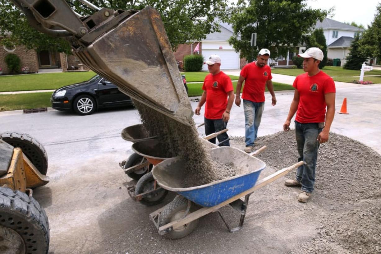 Rodolfo Godinez, from left, Alfredo Rosas Mendoza and Samuel Jimenez, all workers from Jimenez & Sons Landscaping who are in the country on H-2B visas, haul gravel for a project at a home in Lemont, Ill., in July.