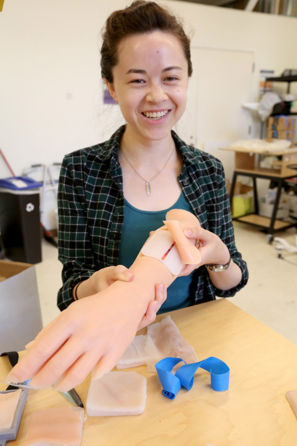 University of Washington engineering student Elizabeth Lee displays her IV arm trainer, a lifelike patch of skin and an arm to help train nurses to take blood samples.