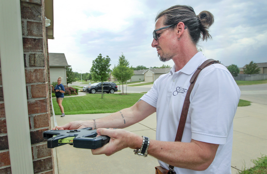 Redemption Church co-pastor Chad Gilstrap measures a home in north Wichita, Kan. He has a real estate appraising business with his wife Jennifer in addition to working at the church.