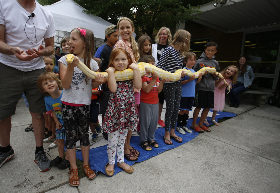 More than a handful of children hold a 13-foot, 20-pound albino Burmese python at the Three Creeks Community Library Saturday.