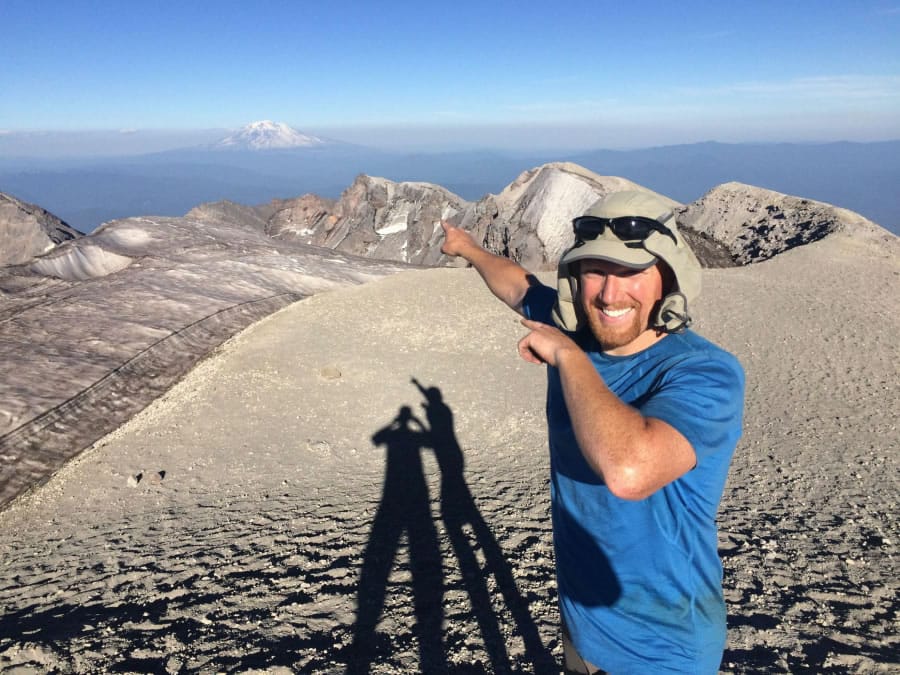 Nick Burson points to Mount Adams – which he’d climb earlier that morning in July 2017 – from the summit of Mount St. Helens.