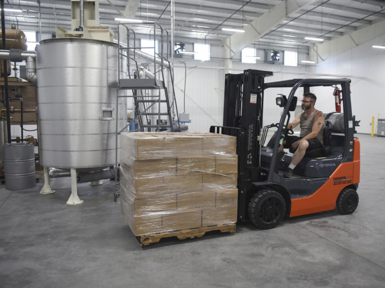 Erick Stewart, floor supervisor at Northwest Adhesives, uses a forklift to transport a wax pallet at the company’s headquarters in Washougal.