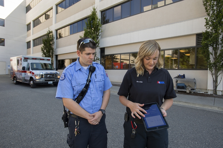 Paramedic Patricio Bustos, left, and paramedic field training officer Brooke Marling of American Medical Response demonstrate how to use the app, Pulsara, Wednesday at PeaceHealth Southwest Medical Center. Local emergency responders began using the app in late May to transmit information to the hospital will en route with patients.