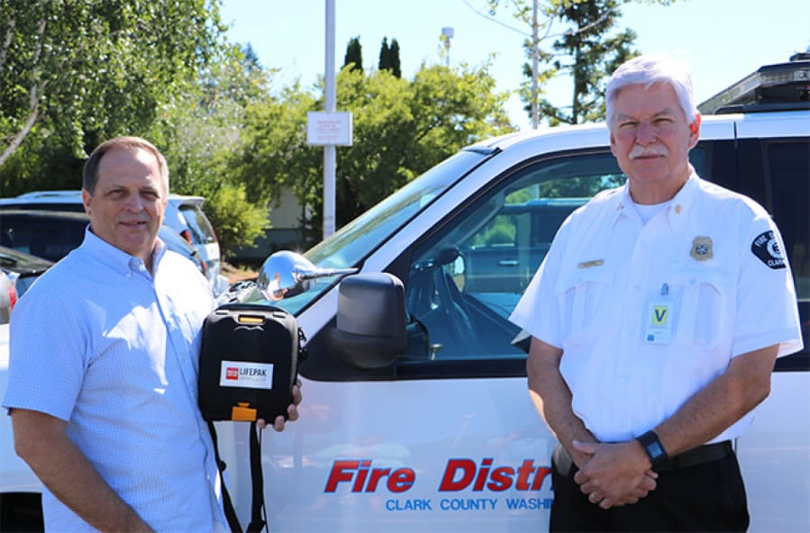 Battle Ground: Battle Ground Public Schools Superintendent Mark Ross, left, and Clark County Fire District 3 Chief Steve Wrightson show the Automated External Defibrillator donated to the district by the fire district and American Medical Response.