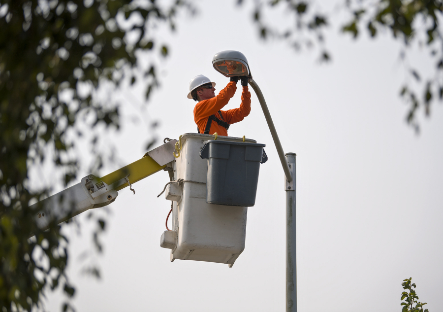 Journeyman lineman apprentice Vince Sorge replaces a high-pressure sodium light fixture with a new LED light fixture in Felida on Tuesday morning. Clark Public Utilities is funding the replacement of 23,000 old light fixtures with the new and more efficient technology.