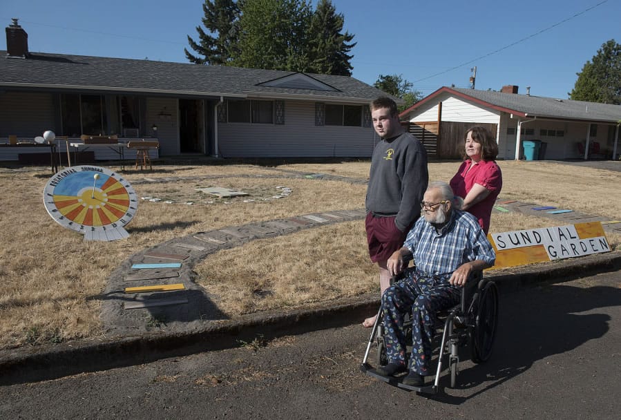 Tom Laidlaw, center; his grandson, Doug Brouhard, left; and his daughter, Debra Brouhard, look over the sundial garden Laidlaw created in his Vancouver Heights neighborhood front yard.