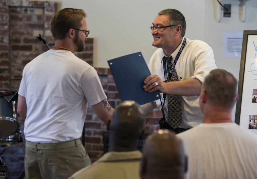 Inmate James Pyles shakes hands with Chaplain Zilvinas Jakstas, right, during the graduation ceremony for the prison’s new program, Language Arts for Healing, at Larch Corrections Center in Yacolt on Thursday. Inmates in the voluntary program spent 16 weeks working with Seattle authors honing their writing skills.