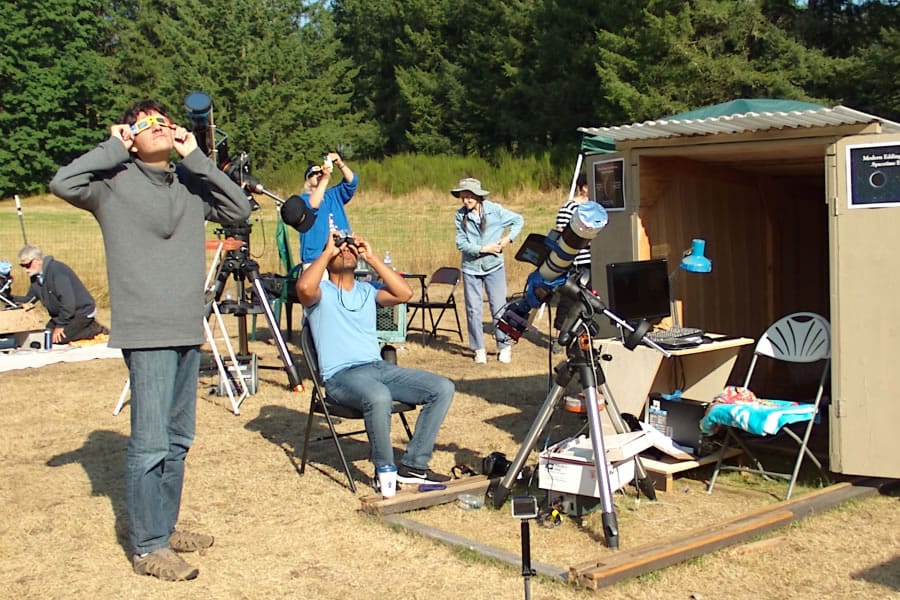 Jacob Sharkansky, standing, from left, Abraham Salazar, seated, and Richard Berry, in background, view the Aug. 21 eclipse while Eleanor Berry looks away from the sun.