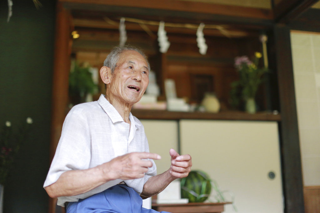 In this Aug. 14, 2017 photo, Tatsuya Yasue, 89-year-old farmer, speaks about his brother Sadao Yasue, who fell in battle during the war in Pacific more than 70 years ago, infant of a household altar at his home in Higashishirakawa, in central Japan's Gifu prefecture. Former U.S. Marine Marvin Strombo will returns Sadao's calligraphy-covered flag he took from the fallen Japanese soldier 73 years ago.