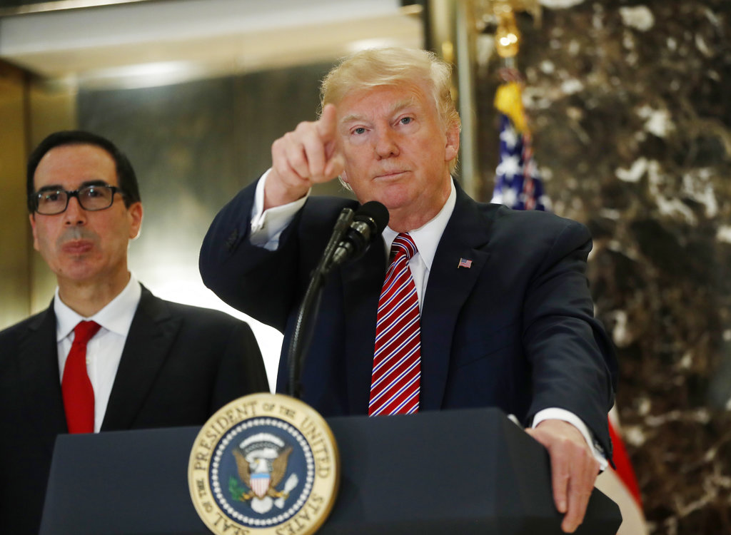 President Donald Trump, accompanied by Treasury Secretary Steven Mnuchin, calls on a reporter while meeting the media in the lobby of Trump Tower in New York, Tuesday, Aug. 15, 2017.