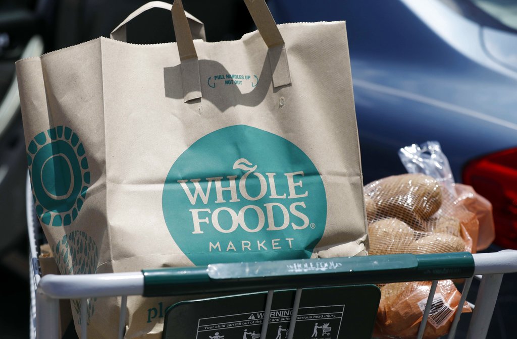 FILE - In this Friday, June 16, 2017, file photo, groceries from Whole Foods Market sit in a cart before being loaded into a car, outside a store in Jackson, Miss. On Wednesday, Aug. 23, 2017, Whole Foods shareholders will be voting on whether to approve Amazon’s $13.7 billion takeover bid of the organic grocer. (AP Photo/Rogelio V.