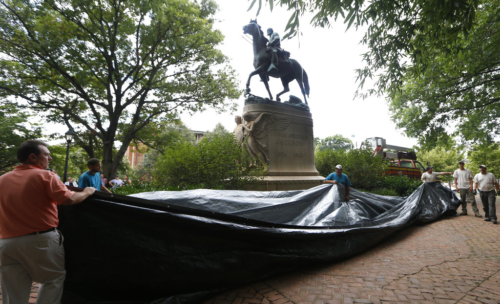 City workers prepare to drape a tarp over the statue of Confederate General Stonewall Jackson in Justice park in Charlottesville, Va., Wednesday, Aug. 23, 2017. The move to cover the statues is intended to symbolize the city's mourning for Heather Heyer, killed while protesting a white nationalist rally earlier this month.