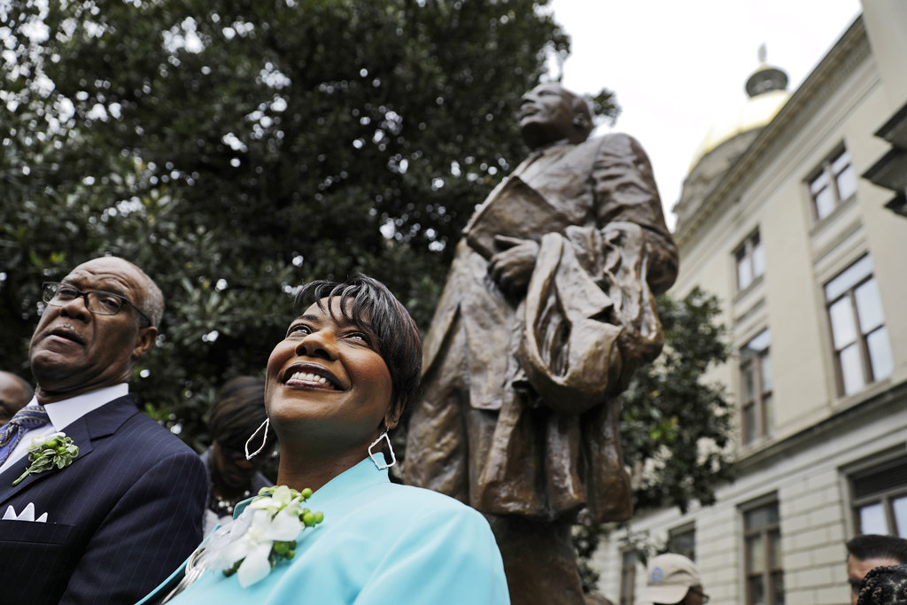 The Rev. Bernice King, right, daughter of the Rev. Martin Luther King Jr., stands under a statue paying tribute to her father, after it's unveiled on the state Capitol grounds in Atlanta, Monday, Aug. 28, 2017. The statue's unveiling Monday came more than three years after Georgia lawmakers endorsed the project. A replica of the nation's Liberty Bell tolled three times before the 8-foot (2.44-meter) bronze statue was unveiled on the 54th anniversary of King's "I have a dream" speech at the march on Washington.