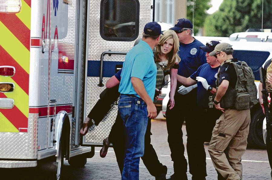 An injured woman is carried to an ambulance in Clovis, N.M., Monday, Aug. 28, 2017, as authorities respond to reports of a shooting inside a public library. A city official says police have taken a person into custody who they believe is responsible for a shooting at the library.