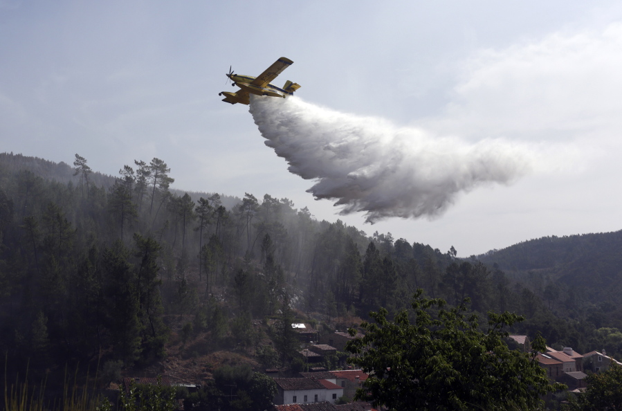 A firefighting plane drops its load to prevent wildfires from reigniting over the village of Agua Formosa, near Vila de Rei, central Portugal on Tuesday.