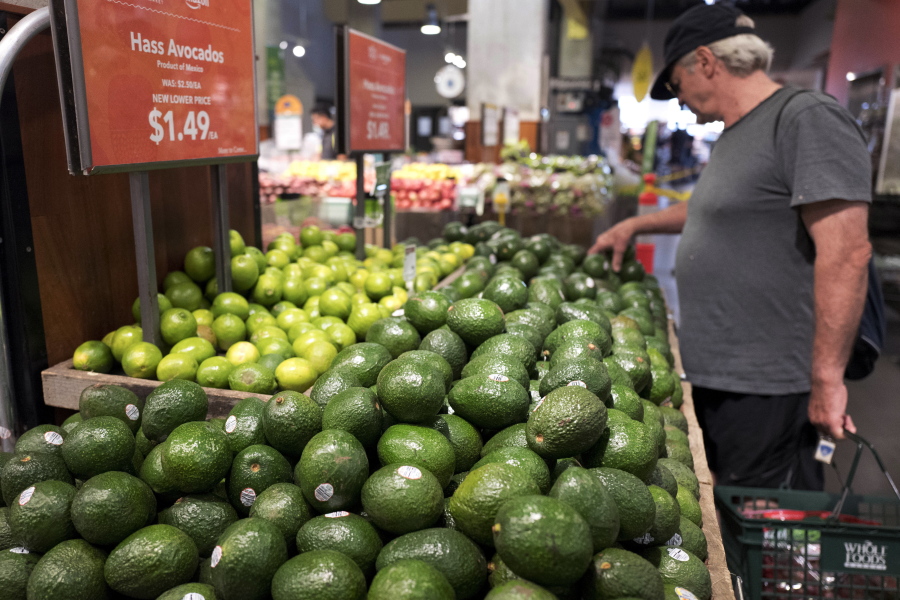 FILE - In this Monday, Aug. 28, 2017, file photo, a man shops for avocados at a Whole Foods Market, in New York. The splashy price cuts Amazon made as the new owner of Whole Foods attracted some curious customers. But whether shoppers who found cheaper alternatives to Whole Foods will come back, or those who never visited will give them a try, may help determine what kind of effect the deal has on how and where people do their grocery shopping.