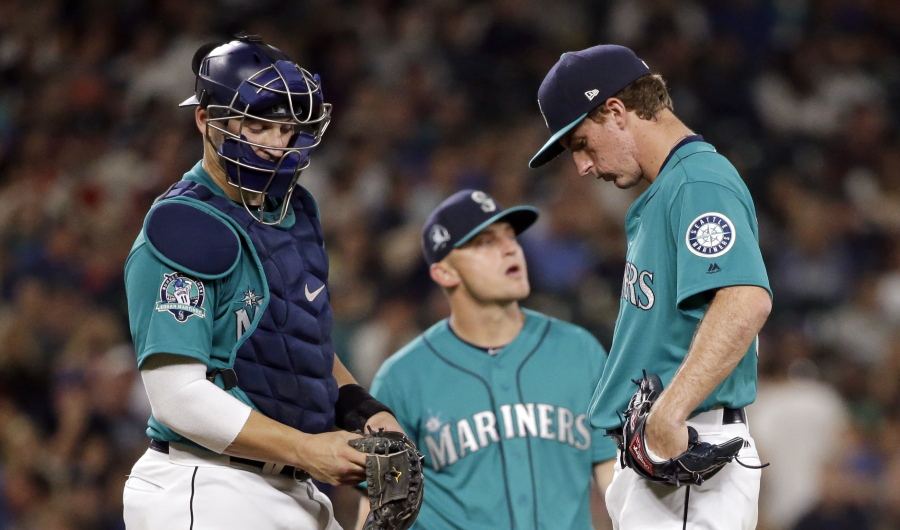 Seattle Mariners relief pitcher Andrew Moore, right, looks down as he waits with catcher Mike Zunino, left, and third baseman Kyle Seager, before Moore was removed during the seventh inning of the team’s baseball game against the Los Angeles Angles on Friday, Aug. 11, 2017, in Seattle.