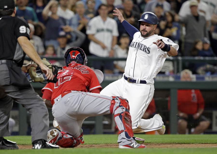 Seattle Mariners' Yonder Alonso, right, slides into a tag at home by Los Angeles Angels catcher Martin Maldonado for the out during the seventh inning of a baseball game Saturday, Aug. 12, 2017, in Seattle.