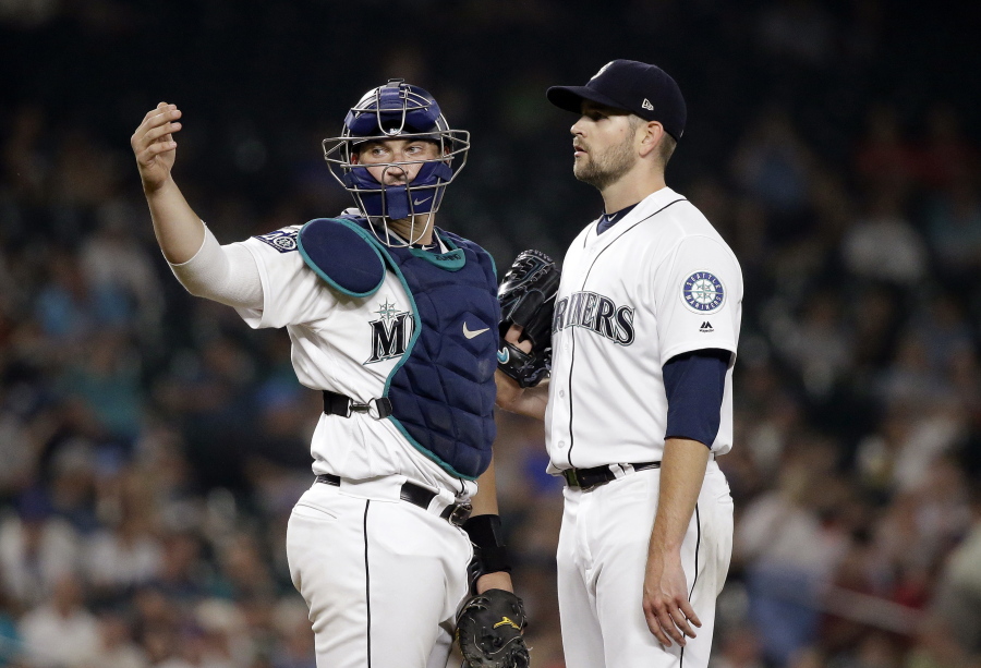 Seattle Mariners catcher Mike Zunino, left, signals to the dugout as starting pitcher James Paxton waits on the mound during the seventh inning of the team’s baseball against the Los Angeles Angels on Thursday, Aug. 10, 2017, in Seattle. Paxton was checked by a trainer and left the game.