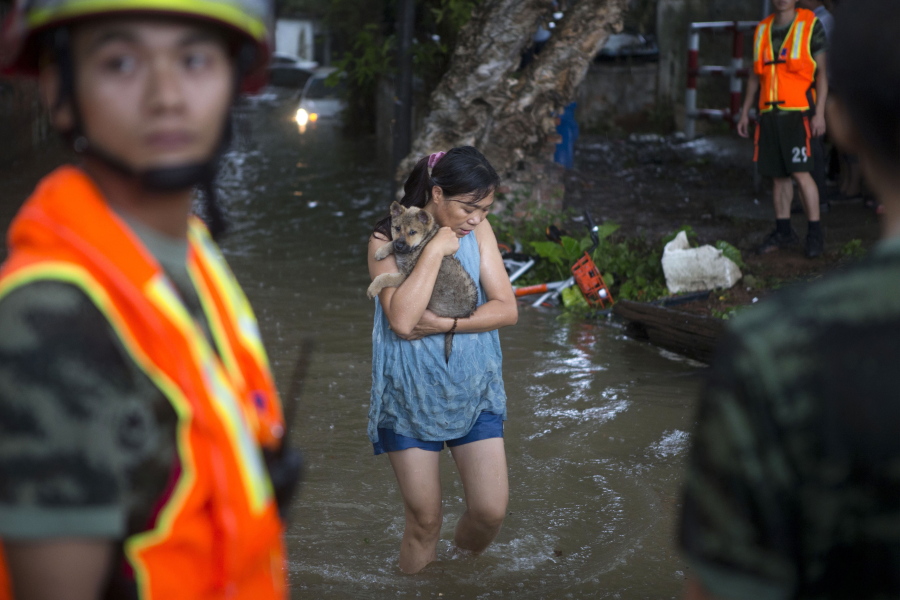 A woman holds on to her pet as they evacuate from flood waters caused by Typhoon Hato and the tide in Guangzhou in southern China’s Guangdong province Wednesday. Thousands of people were evacuated from parts of the mainland coast ahead of the storm’s arrival, China’s official Xinhua News Agency reported.
