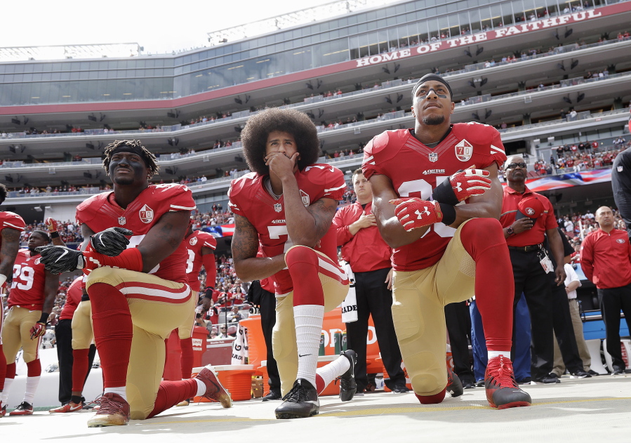 San Francisco 49ers outside linebacker Eli Harold, quarterback Colin Kaepernick, center, and safety Eric Reid kneel during the national anthem before a game in 2016.
