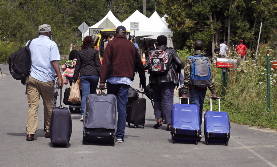 A family from Haiti approach a tent in Saint-Bernard-de-Lacolle, Quebec, stationed by Royal Canadian Mounted Police, as they haul their luggage down Roxham Road in Champlain, N.Y., Monday, Aug. 7, 2017. Officials on both sides of the border first began to notice last fall, around the time of the U.S. presidential election, that more people were crossing at Roxham Road. Since then the numbers have continued to climb.