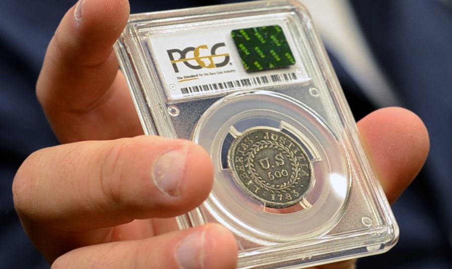 In this Monday, July 31, 2017, image made from a video, David McCarthy, a senior numismatist at Kagin’s, holds what is believed to be the first coin ever struck by the U.S. government at the World’s Fair of Money in Denver, Colo. The coin is on display this week at the World’s Fair of Money in Denver.
