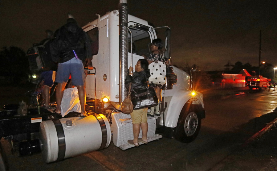 Residents cling to a commercial truck as it carries them to safety following flooding to their homes, late Monday night in Lake Charles, La. Almost constant rain over the last two days from Harvey, overcame the city’s drainage system, flooding several subdivisions and necessitating home rescues. (AP Photo/Rogelio V.