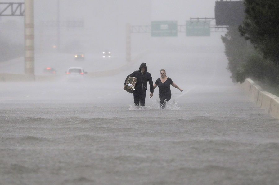 Two people walk down a flooded section of Interstate 610 in floodwaters from Tropical Storm Harvey on Sunday, Aug. 27, 2017, in Houston, Texas. (AP Photo/David J.