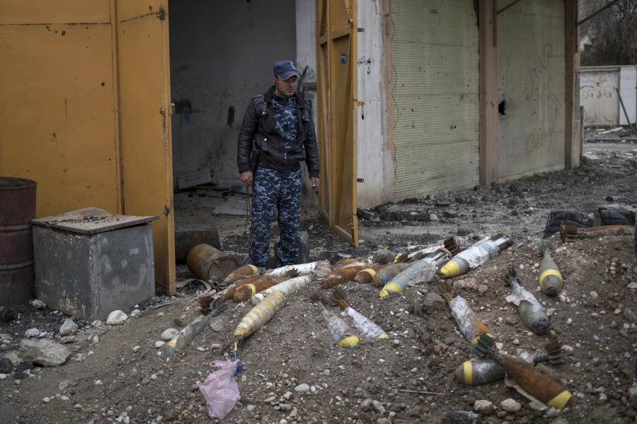 A member of the Iraqi Federal Police stands next to unexploded bombs left by Islamic State group militants March 22 in Mosul, Iraq. The city is littered with explosives, many hidden by Islamic State fighters and set to be triggered by the slightest movement.