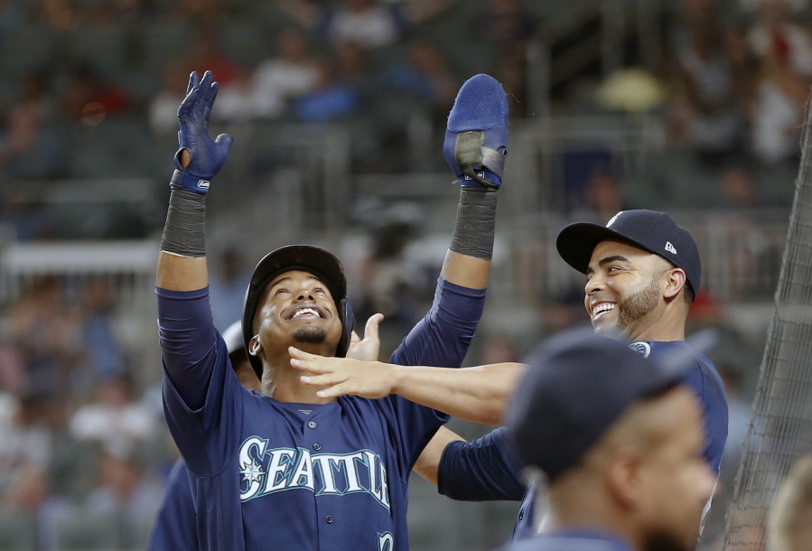 Seattle Mariners' Jean Segura (2) celebrates with Nelson Cruz, right, after scoring on a two base hit by Taylor Motter inning in the eighth of a baseball game against the Atlanta Braves Wednesday, Aug. 23, 2017, in Atlanta.