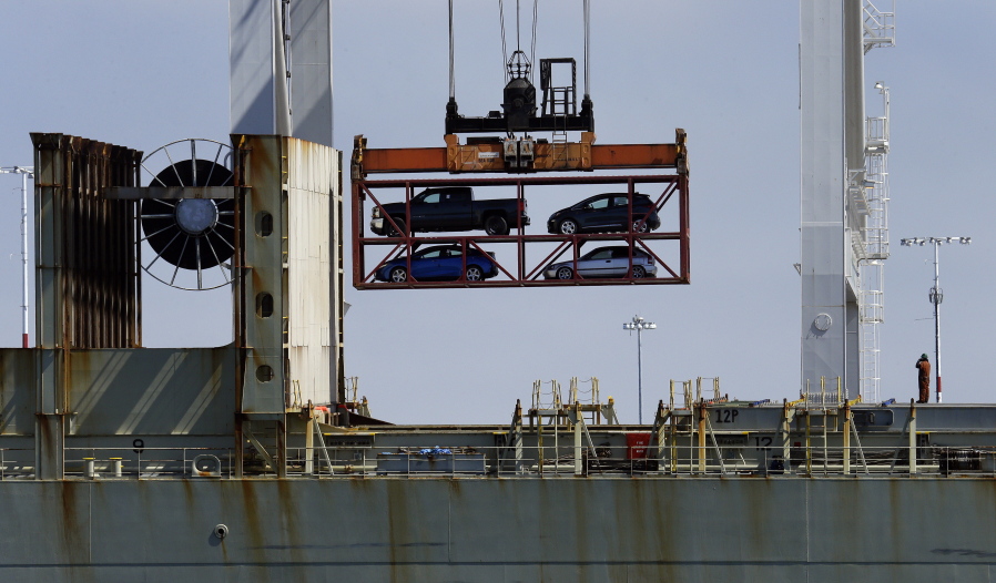 FILE - In this July 13, 2017 file photo, a crane transporting vehicles operates on a container ship at the Port of Oakland, in Oakland, Calif. A key draw for foreign assembly plants and investment has been Mexico’s low wages. With many workers unable to afford the vehicles Mexico produces, the country exports about three times as many cars as are purchased domestically, most to the United States.