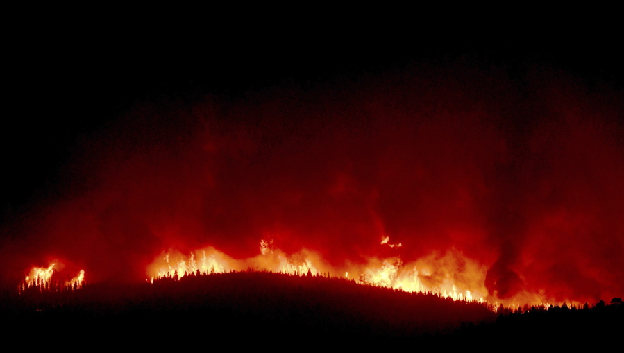 A wall of flames hundreds of feet high burns early Thursday on a ridge above Rowan Road south of Lolo, Mont. More than 500 homes have been evacuated; no homes have been reported burned.