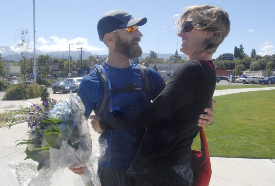 The Rev. Joe DeScala, director of Mended church, is greeted by his wife, Makayla DeScala, at the completion of his 1,376-mile trek around Washington on July 27 in Port Angeles. DeScala made his running, bicycling and kayaking journey to raise funds for orphans and widows.