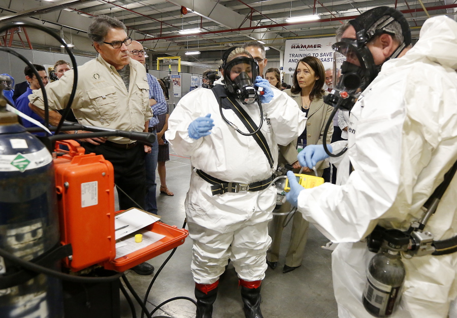 Energy Secretary Rick Perry, left, closely observes as worker trainers Joni Spencer, center, and Dean Beaver prepare to give a respirator demonstration Tuesday at the HAMMER Training Facility in Richland. Rep. Greg Walden, R-Ore., stands next to Perry and Sen. Maria Cantwell, D-Wash., stands in between the workers at right.