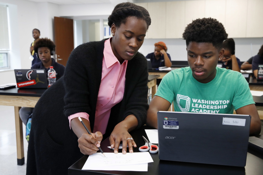 Britney Wray, a math teacher at Washington Leadership Academy in Washington, D.C., helps sophomore Kevin Baker, 15, with a math problem during class.