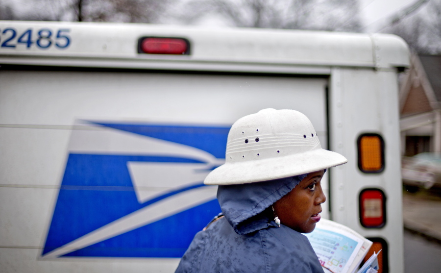 FILE - In this Feb. 7, 2014 file photo, U.S. Postal Service letter carrier Jamesa Euler delivers mail in the rain in Atlanta. Buffeted by threats from Amazon drones and Uber to delivery by golf cart, the beleaguered U.S. Postal Service is counting on a different strategy to stay ahead in the increasingly competitive package business: more freedom to raise your letter prices.