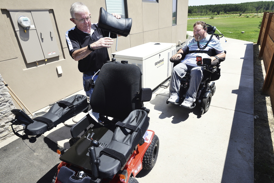 Pete Hedberg, with Pacific Healthcare Associates, puts a headrest on a new all-terrain wheelchair July 18 as Nels Hadden watches at his home in Walla Walla. Hadden was paralyzed nearly nine years ago while helping a motorist on Interstate 84 near Arlington, Ore. E.J.