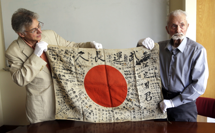 WWII veteran Marvin Strombo, right, and Obon Society executives director Rex Zika hold up a Japanese flag with names written on it in Portland. Strombo recovered the flag from a dead Japanese soldier in the Pacific more than 70 years ago and now, at age 93, will return the flag to the Japanese man’s surviving siblings.