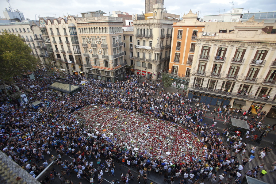 People stand around a memorial tribute of flowers and messages Saturday on Las Ramblas promenade in Barcelona, Spain, at the end of a demonstration condemning the attacks that killed 15 people last week.