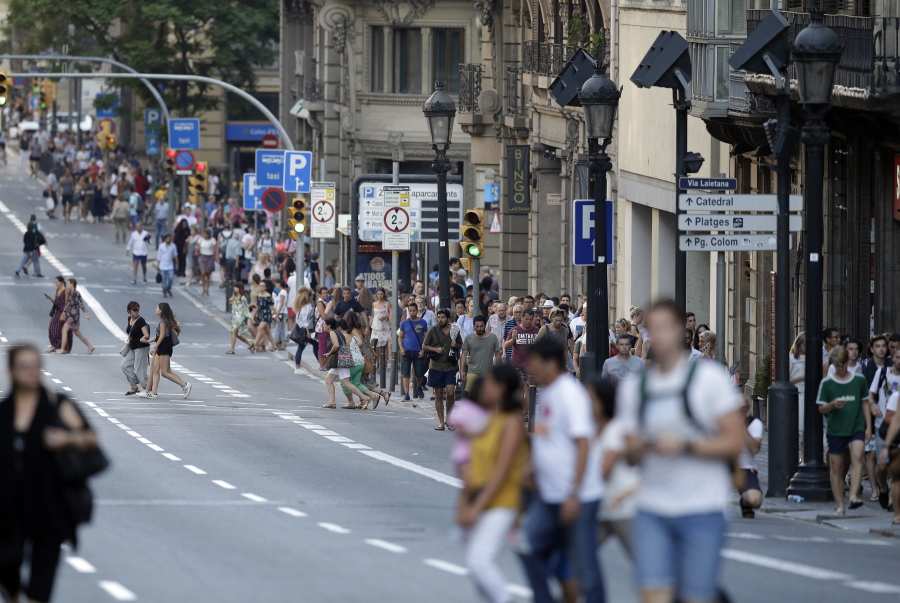 People walk down a main street in Barcelona, Spain, Thursday, Aug. 17, 2017. Police in Barcelona say a white van has mounted a sidewalk, struck several people in the city’s Las Ramblas district.