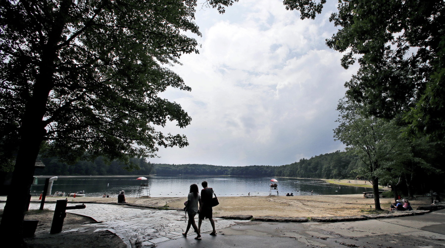 A couple walks along the shore of Walden Pond in Concord, Mass., on July 12. Two centuries after Thoreau’s birth, people are still following in Thoreau’s footsteps to discover Walden Pond, the little lake he immortalized.